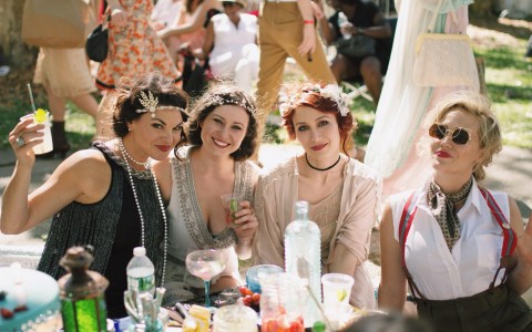 Four women having drink outdoors in Jazz Age attire